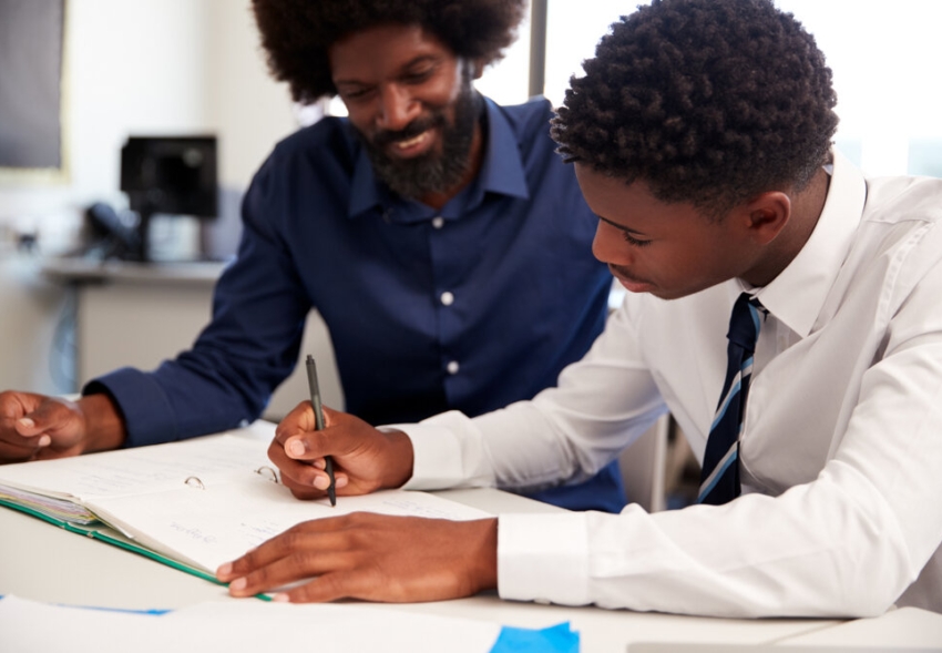 Teacher helping a young student with his work.